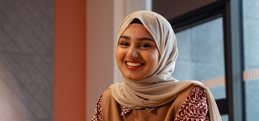 A smiling student sitting in a meeting room.